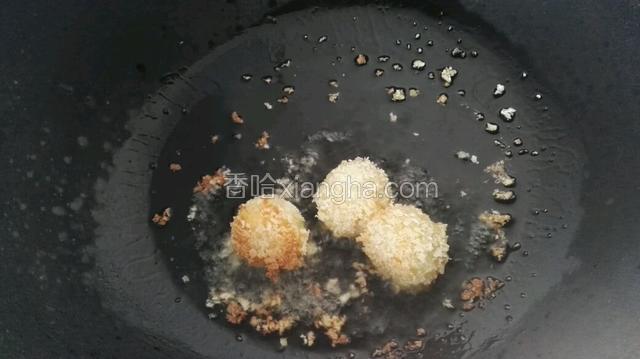 将过好面包糠的土豆球放入锅中炸至金黄