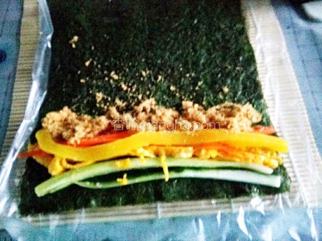 翻面，米饭朝下，在紫菜上放胡萝卜，黄瓜，鸡蛋，腌制萝卜和肉松