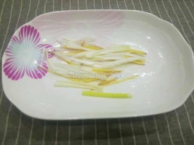 在蒸鱼盘中铺上葱丝和姜丝。