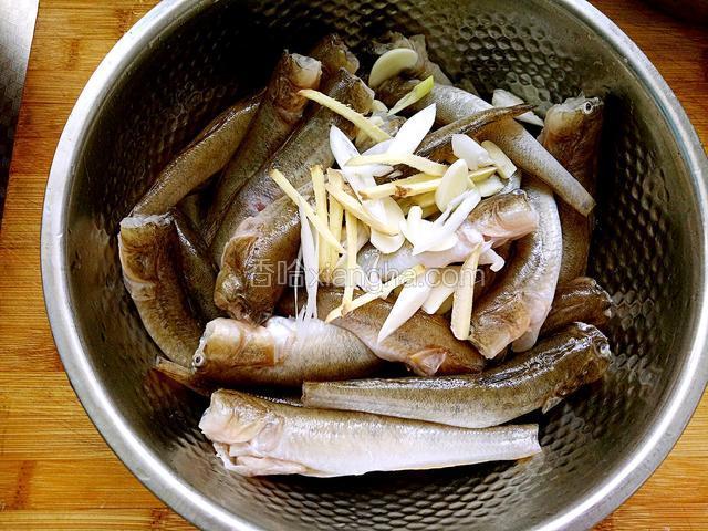 将鱼放入盆中，铺上葱片姜丝蒜片