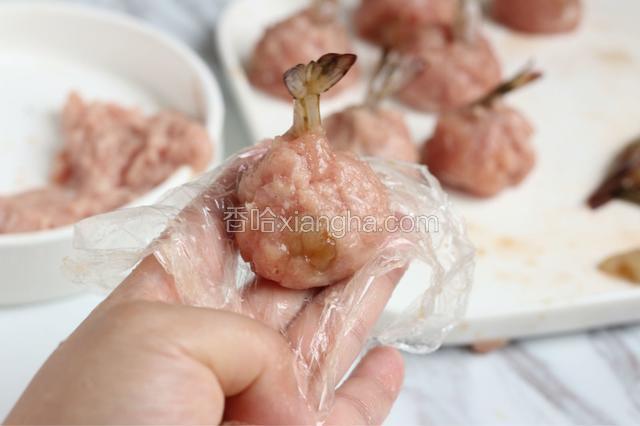 处理好的虾裹上肉馅，隔着保鲜膜搓成圆球。