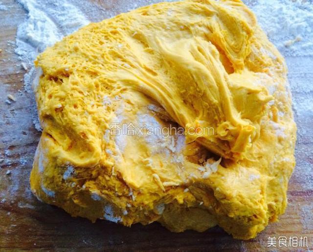 取出发好的南瓜面放面板加适量的小苏打粉揉面，