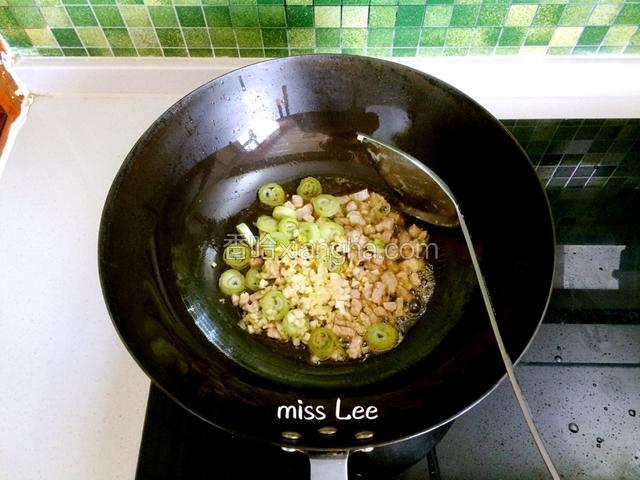 煸至肉色发白时加入葱段、姜末和蒜蓉炒香；