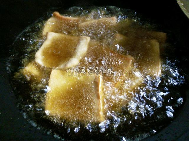 锅中倒稍多的油烧热后下豆腐片大火煎炸，一面金黄后再翻面煎另一面。