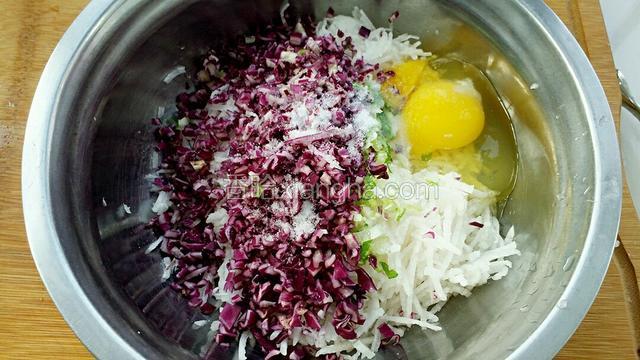 把紫甘蓝、小葱和萝卜丝放到一起，调入适量食用盐，打入鸡蛋搅拌均匀。