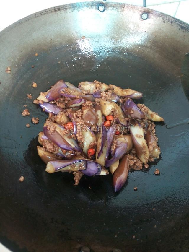 接着放入炸好的茄子一起翻炒，加少许盐、糖，适量的味极鲜，和适量清水翻炒均匀