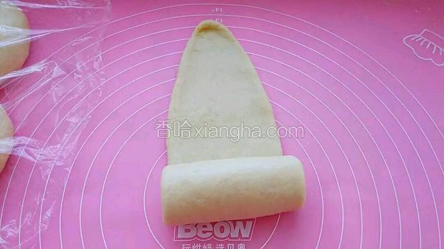取一个面团揉匀后擀成长舌状，从一头轻轻卷起。