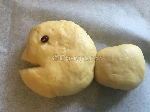 取大面团按扁做鱼头和身子，再取小面团按扁做鱼尾巴，在鱼头上剪个口做鱼嘴，放个红豆做鱼的眼睛。