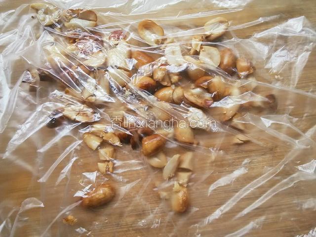 待花生米晾了，去除外瓤，装进保鲜袋，用擀面杖压碎