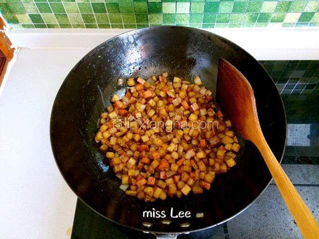接着一同放入土豆丁和肉肠丁翻炒，加入适量老抽、食盐、辣椒粉和孜然粉上色调味；