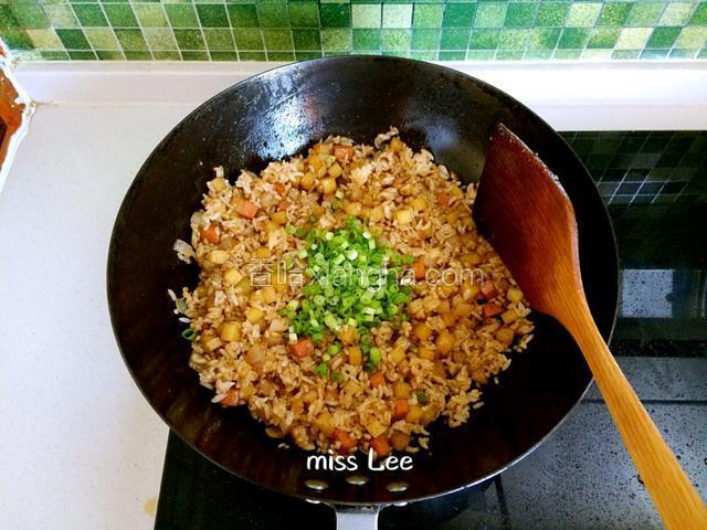 小火翻炒，当米饭均匀上色，吸收油分变得分散饱满时，撒入葱花；