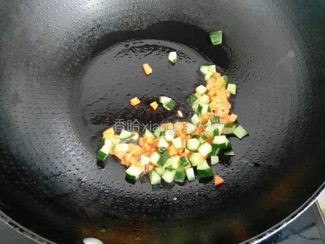 锅中倒适量的油，烧热加入切好的红萝卜丁、黄瓜丁翻炒