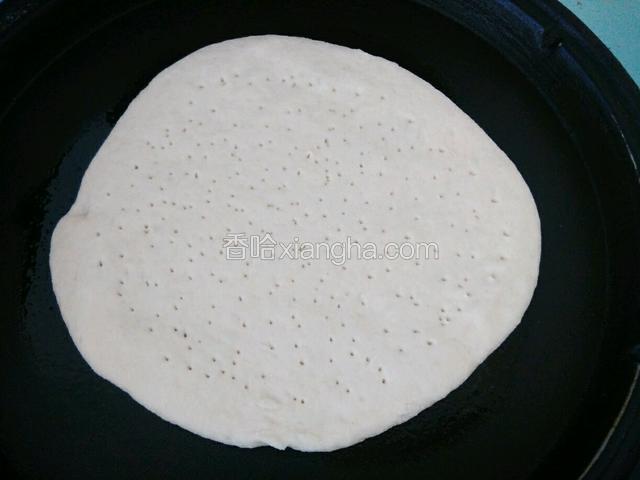 面发酵好后，擀成圆形面皮(要擀成边缘厚，中间薄)，用牙签或叉子在面皮上扎孔排气。