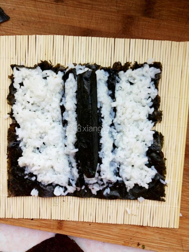 嘴巴放到米饭中间,依次放上三根黄瓜,摆好位置卷起来