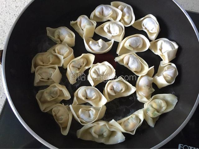 将馄饨放入平底锅中，馄饨之间间隔开，以免粘连一起，沿锅边倒入适量温水，水约淹至馄饨的四分之一。