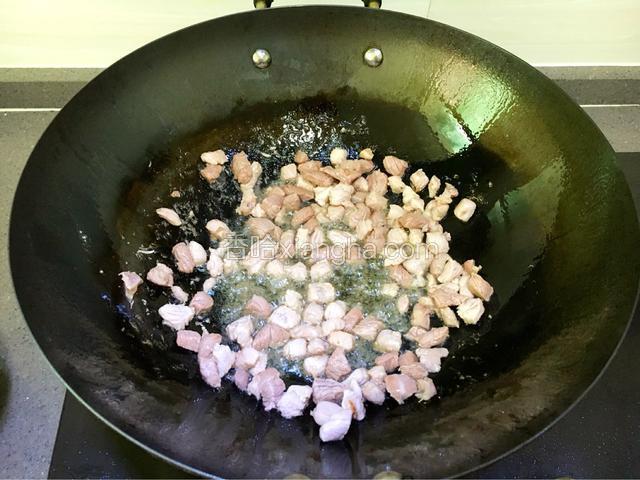 锅中放入适量油，先把猪肉丁炒至变色发白。