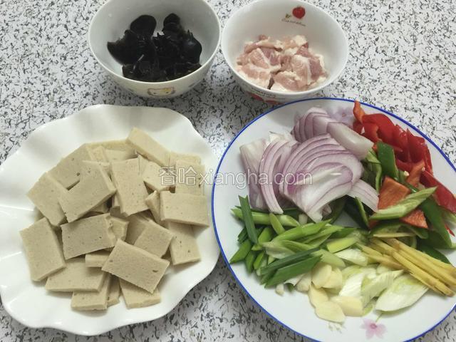 千叶豆腐、五花肉、青红椒、洋葱切片，姜切丝，葱和蒜苗切段，五花肉放入半勺盐和一勺水淀粉抓匀