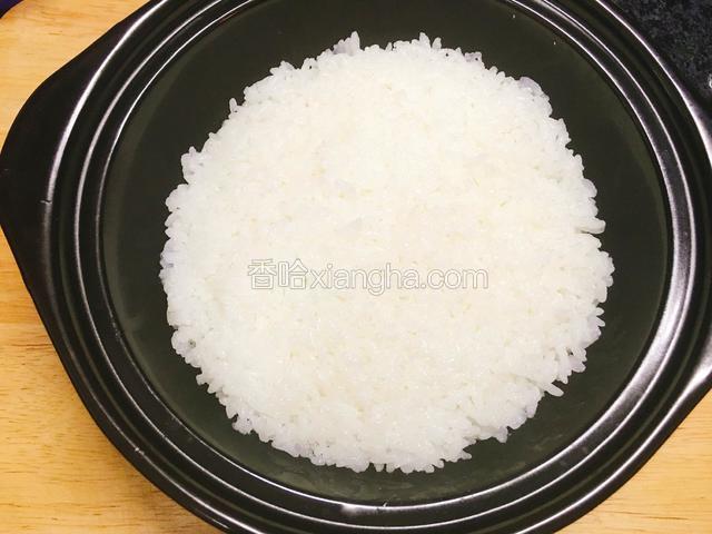 石锅内涂一层芝麻油，放入白米饭，压平。