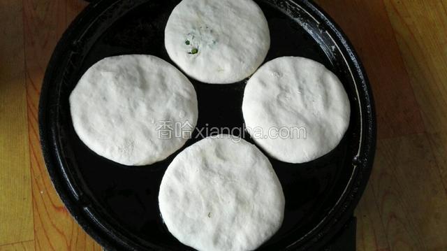 电饼铛放少量油，油热后把包子褶朝下用手压成圆饼。