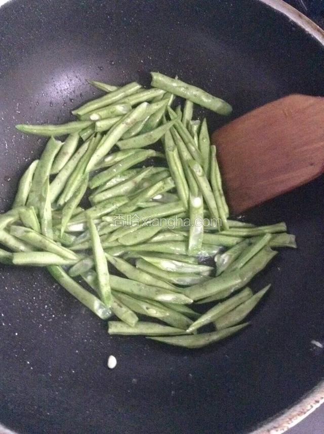 锅中放适量玉米油，下四季豆煸炒。