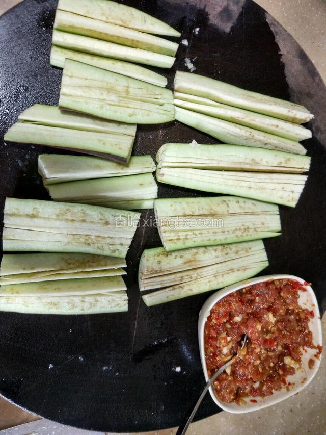 把肉和大蒜放入盛有辣椒酱的碗里！加适量的生抽，料酒，鸡精，胡椒粉，生粉，拌均匀，腌制半个小时左右！茄子一分二，然后切一片片的！