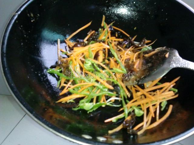锅内留底油下葱姜爆香下黑木耳，胡罗卜，青椒翻炒。