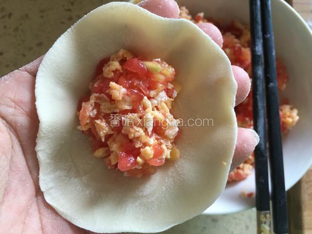 取一个饺子皮，中间放入适量的西红柿鸡蛋馅儿。