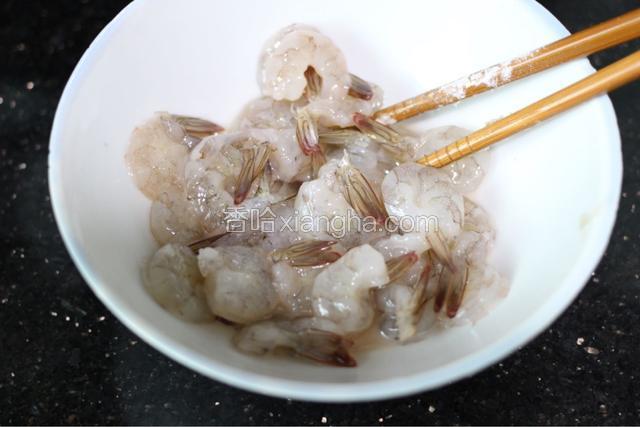 虾仁放碗里加入料酒，盐和淀粉，料酒多放一点，搅拌均匀，腌制一会