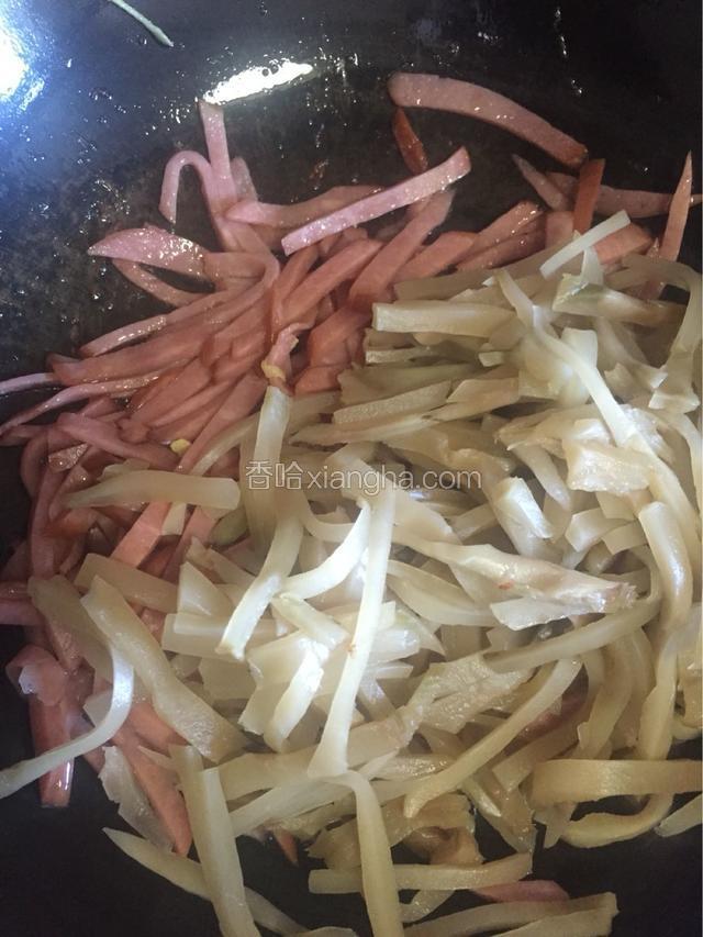 先下火腿肠丝，再下榨菜丝，先让火腿肠丝在油锅里煎炸一下