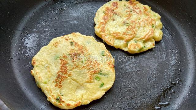锅里加少许油烧热，舀两勺面糊进去，用勺子摊成圆形。煎至一面金黄，翻面，再煎好另一面。依次做完所有的。