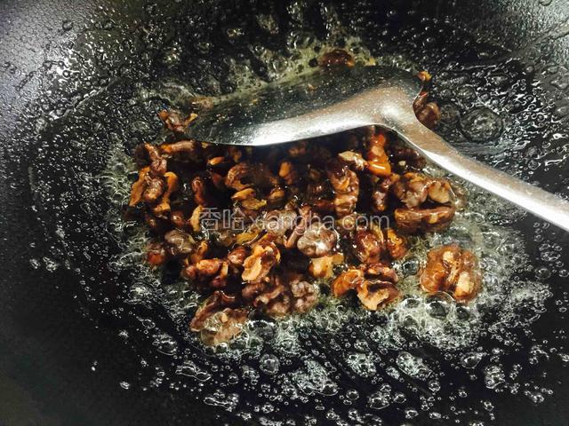 把核桃仁倒进去，不停的用铲子翻炒。