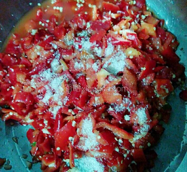 看到辣椒腌制出很多水份时，将腌制出来的水倒出不要，放入白糖和大蒜头搅拌均匀。