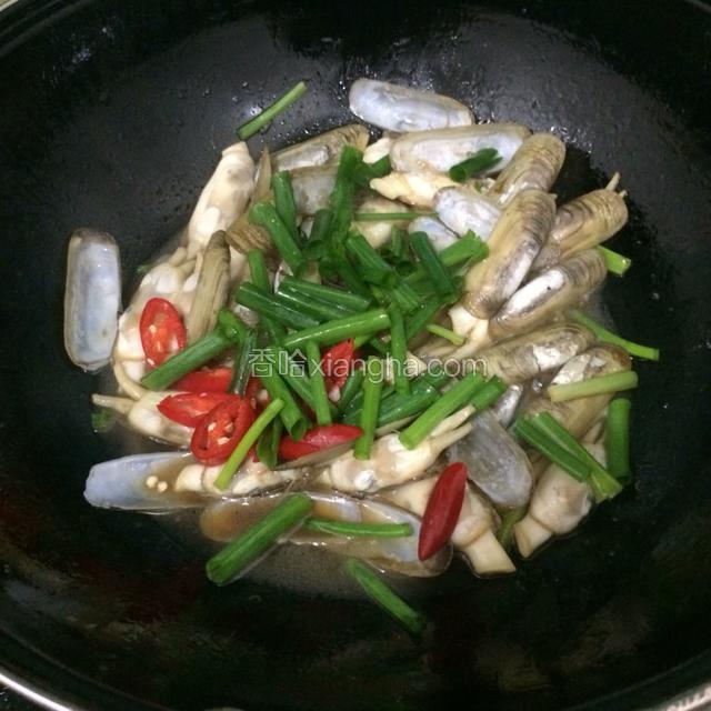 海蛏爆炒的时候会出水，大火烧开，加一点点生抽，白糖调味，放入剩余的葱段，红椒圈翻炒断生即可关火出锅。