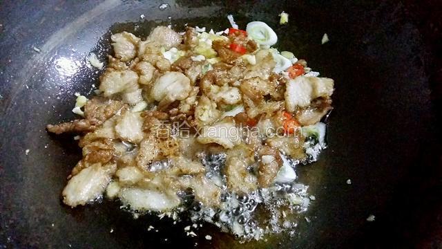 待五花肉炒到出油状态放入葱姜蒜辣椒末煸香