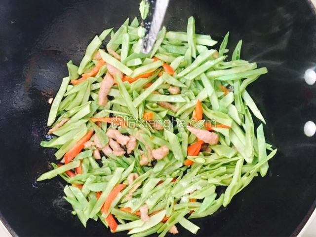 倒入扁豆丝和红椒丝，加适量盐翻炒