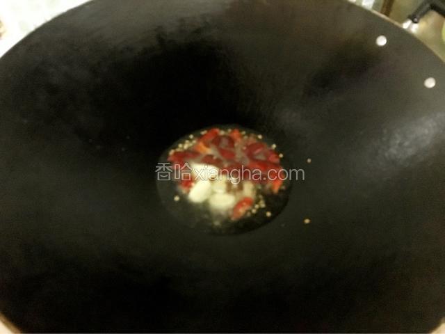 锅中放入适量油烧热，放入一半的辣椒花椒蒜头爆香