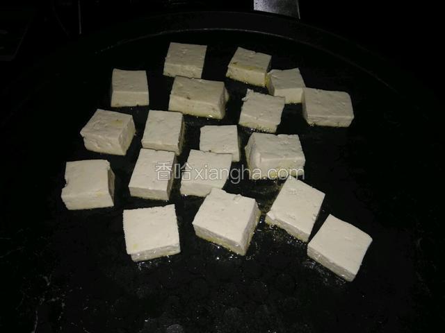 平底锅放油烧热，放入豆腐块煎制。因为是夜里做的，所以光线有点暗。