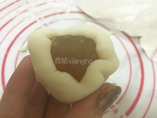 手沾上适量的熟糯米粉把冰皮揉成团，再按扁把凤梨馅放入。