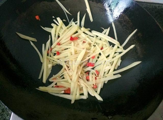 起油锅，放适量油，爆香蒜末，倒入红椒粒和土豆丝翻炒，放盐调味。