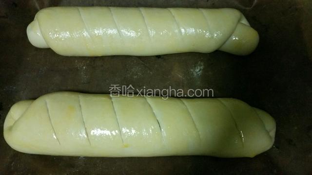 发好的面包取出用刀片斜着划几道深口，表面刷上预留的蛋液