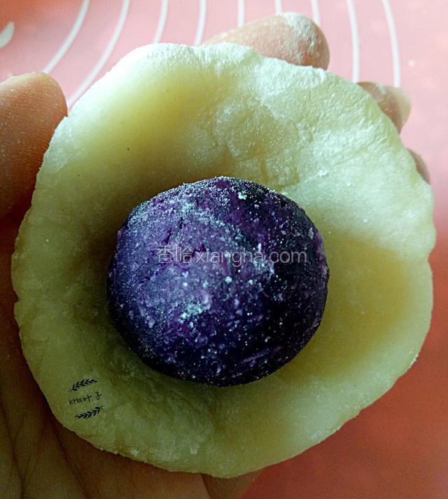 双手抹上熟粉，把粉球摊薄，放进紫薯球。