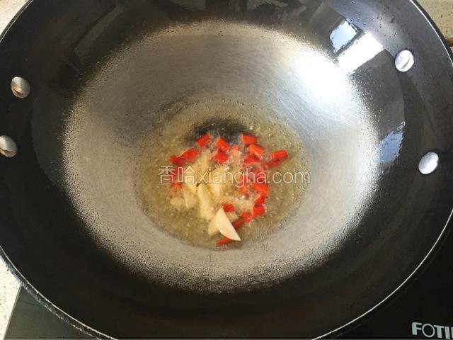 锅中倒入适量油，中火烧热滑锅，下小米椒、蒜片爆香。