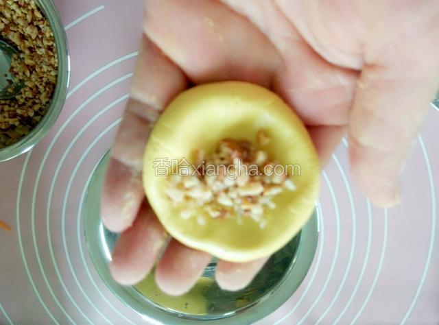 放花生馅入窝状，从四周向中心闭合，再揉圆，在糕粉中滚一滚。