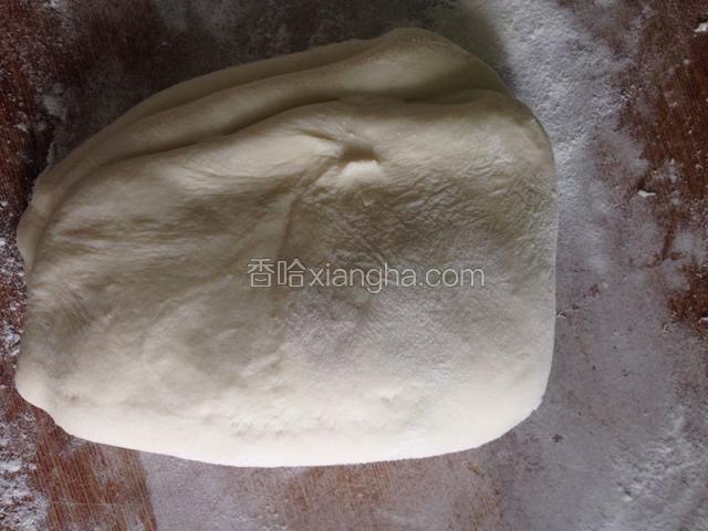 第二天早上取出团菜板上撒上一些面粉，把面团气排出，面团对折一侧重按压用手