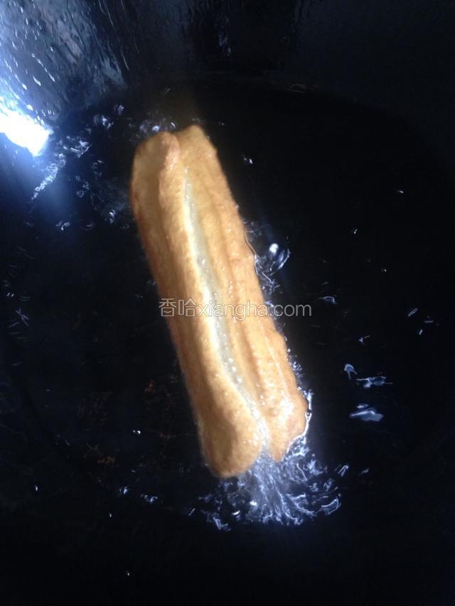 手拿在油条两端拉长，放入六成热油锅中，火候要控制好，不停的用筷子翻动，之金黄色即可捞起放在吸油纸上