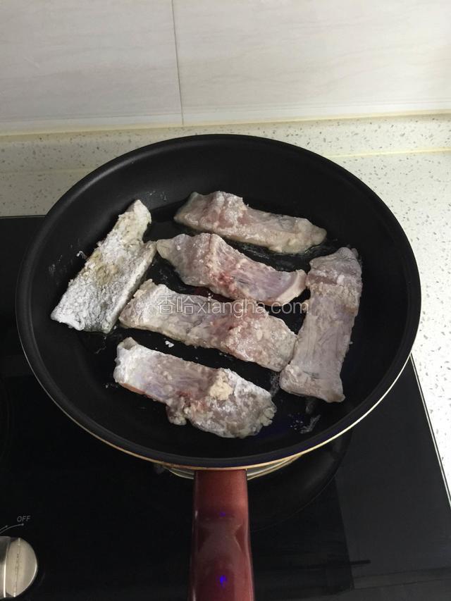 不粘锅小火倒入适量花生油摆入裹好淀粉的鱼片。