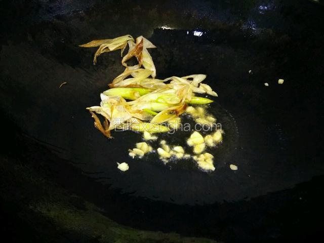 看大葱炸的焦黄，铲到一边，放入蒜蓉爆香，给盐