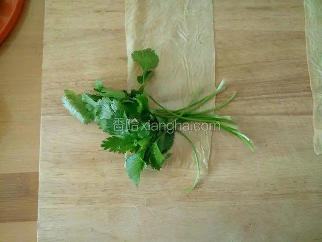 把香菜放在豆腐皮底部，从下往上卷