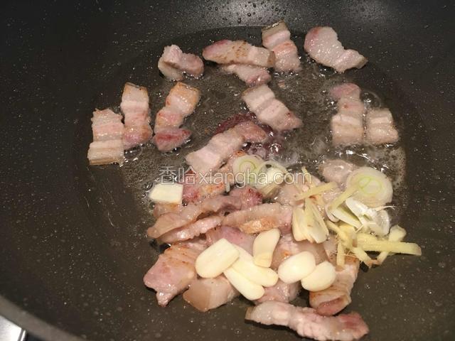 把五花肉快炒焦时，放入葱姜蒜爆香。