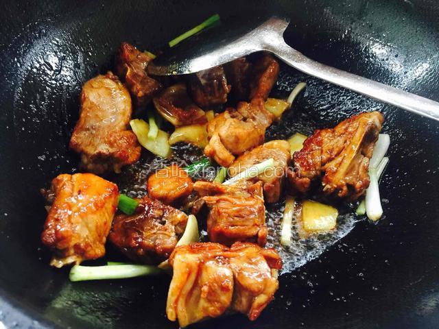 排骨上色后放入姜片葱段翻炒出香味。